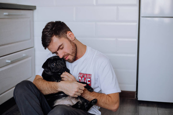 The guy gently hugs a pug dog - Фото, зображення