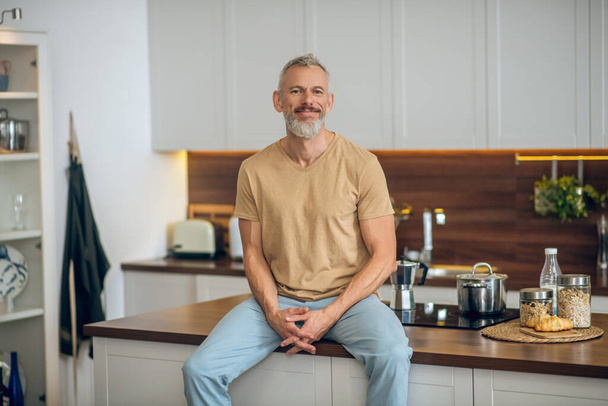 Mature man in beige tshirt in the kitchen at home - Fotoğraf, Görsel