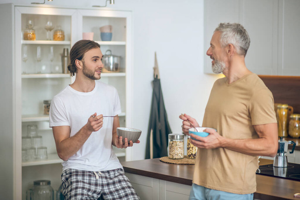 Smiling couple having coffee and talking in the kitchen - Foto, imagen