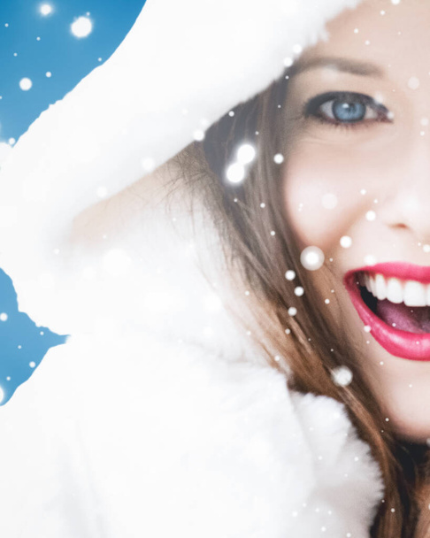 Feliz Natal e férias de inverno retrato de jovem mulher de casaco de pele com capuz branco, neve no fundo azul, moda e estilo de vida - Foto, Imagem