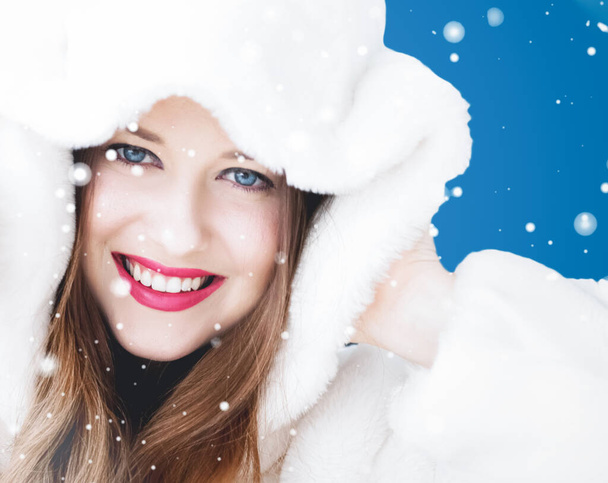 Hyvää joulua ja talvilomaa muotokuva nuori nainen valkoinen hupullinen turkki, lunta sinisellä pohjalla, muoti ja elämäntapa - Valokuva, kuva