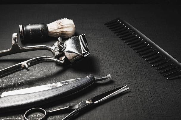 vintage barber tools. dangerous razor, hairdressing scissors, old manual clipper, combs, shaving brush. black monochrome. black background. - Photo, Image