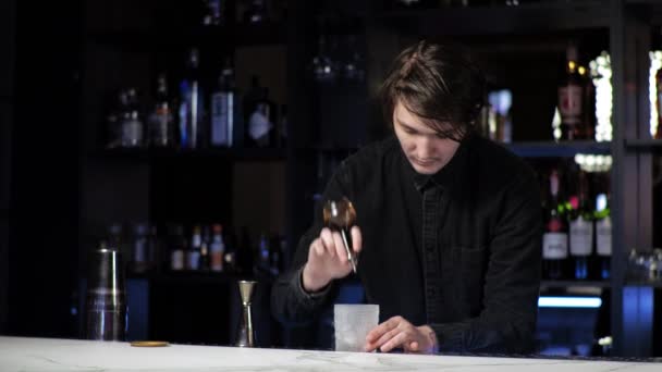 jonge beginnende barman stagiaire het bereiden van een cocktail zorgeloze kerel mengt drinken en ijs in een shaker - Video