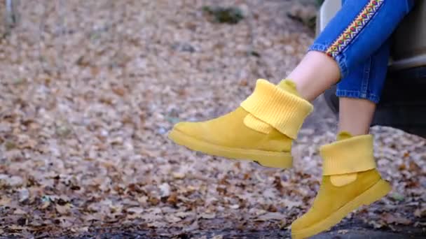 Jovem mulher balança pernas vestindo botas amarelas elegantes preso fora do automóvel moderno - Filmagem, Vídeo