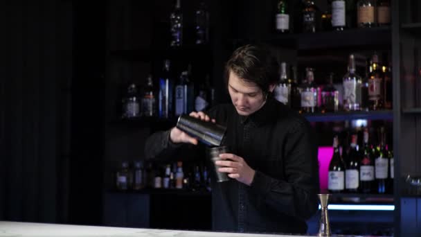 Nuori noviisi baarimikko harjoittelija valmistelee cocktail Huolimaton kaveri Sekoittaa juoda ja jäätä ravistin - Materiaali, video