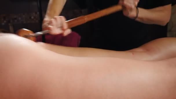 Madeira terápia. Fiatal nő kap anti-cellulit masszázs kezelés spa szalonban. a terapeuta gyógymódokat készít a test formájának javítására. Agresszív küzdelem a zsír ellen. Gyógykezelés. 4 k videó - Felvétel, videó