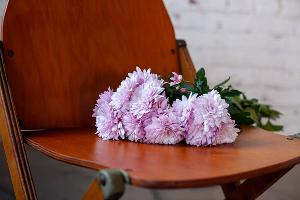 Retro wooden collapsible chair with flowers against a white brick wall - 写真・画像