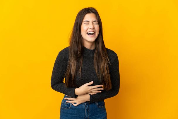 Teenager Brazilian girl isolated on yellow background smiling a lot - Foto, afbeelding