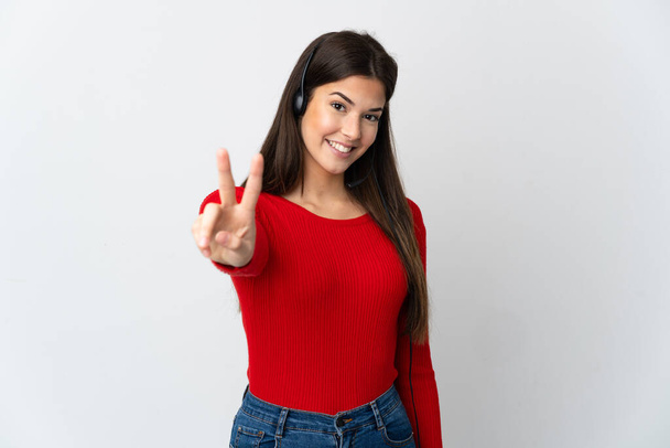 Young Brazilian telemarketer girl over isolated background smiling and showing victory sign - Фото, изображение