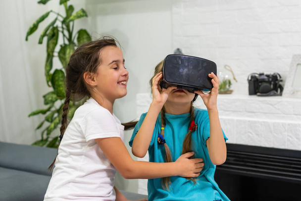 dos niñas usando gafas de auriculares de realidad virtual. concepto de tecnologías modernas - Foto, imagen