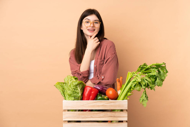 Mladá farmářská dívka s čerstvě sklizenou zeleninou v krabici s brýlemi a úsměvem - Fotografie, Obrázek