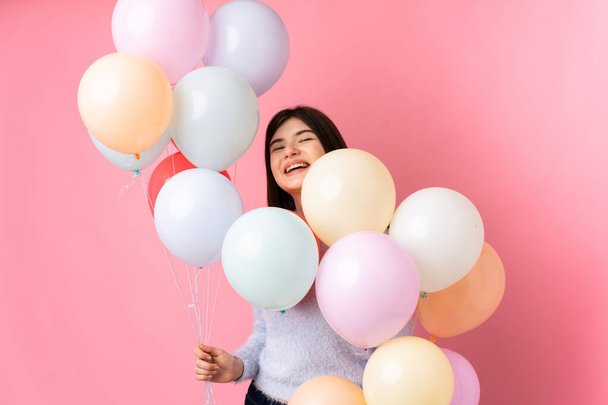 Young Ukrainian teenager girl holding lots of balloons over isolated pink background - Photo, Image