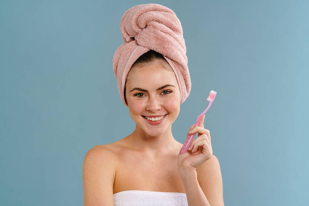Nice happy girl wearing towels posing with toothbrush isolated over blue background - Foto, Bild