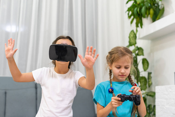 Kaksi pientä tyttöä käyttää virtuaalitodellisuuskuulokkeita. nykyaikaisen teknologian käsite - Valokuva, kuva
