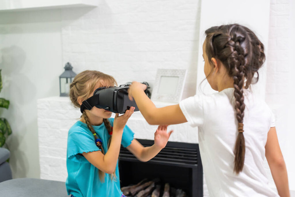 Две маленькие девочки используют очки из гарнитуры виртуальной реальности. концепция современных технологий - Фото, изображение
