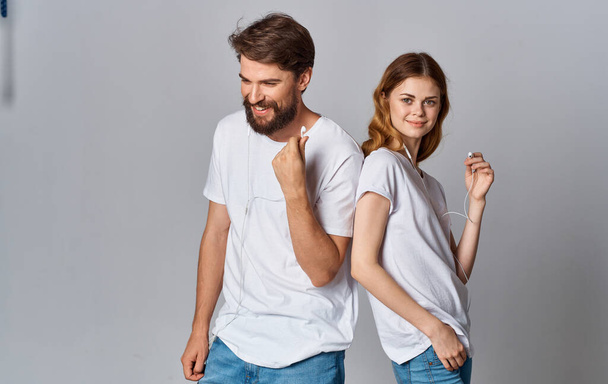 šťastný muž a žena ve sluchátkách na šedém pozadí vypadat a stát zády k sobě - Fotografie, Obrázek