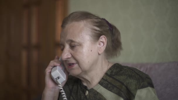 Nagymama érzelmileg beszél a vezetékes telefonon. Az öreg hölgy összezavarodott, hogy olyasvalakitől hallja az információt, akivel beszél.. - Felvétel, videó