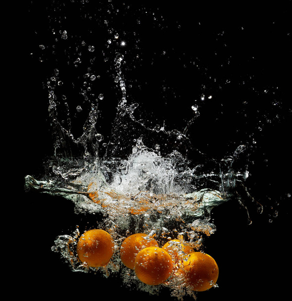 Five fresh oranges falling in water on a dark background - Fotografie, Obrázek