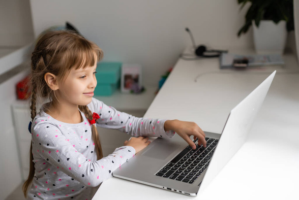 Little girl studying online using her laptop at home - Photo, Image