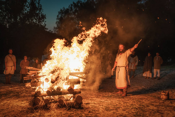 Cedynia, Poland, June 2019 Pagan reenactment of Kupala Night, called in Poland Noc Kupaly, shaman greeting strangers with knife at bonfire. Slavic holiday celebrated on the shortest night of the year - Fotoğraf, Görsel