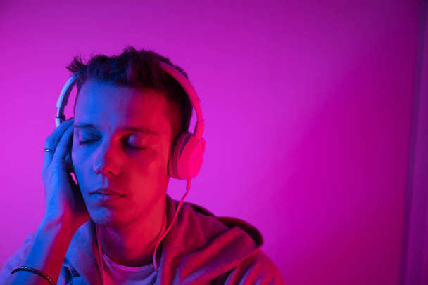 Férfi zenét hallgat fejhallgatóval, színes háttérrel. Zenei poszter - Fotó, kép