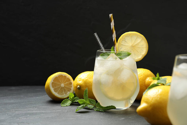 Natural lemonade with mint on grey table against black background, space for text. Summer refreshing drink - Fotografie, Obrázek