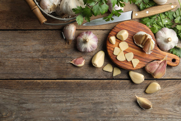 Flat lay composition with fresh sliced and whole garlic on wooden table, space for text. Organic product - Photo, Image