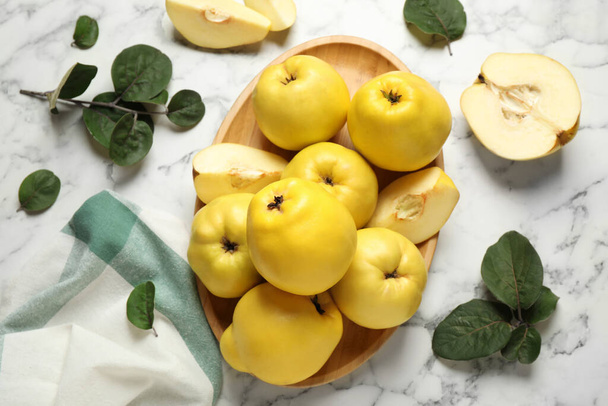Fresh ripe organic quinces with leaves on white marble table, flat lay - Foto, Bild