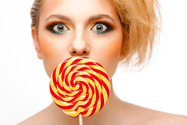 woman licks candy with beautiful make-up - Foto, afbeelding