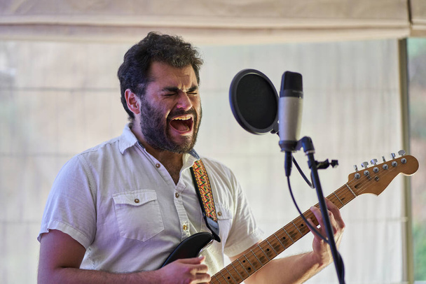 Musiker singt mit Wut, Leidenschaft und viel Gefühl auf seiner Gitarre - Foto, Bild