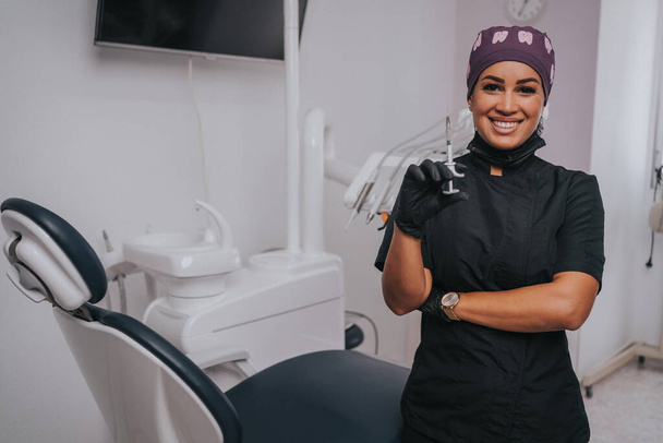 Giovane donna caucasica bionda che apre la bocca mentre il dentista etnico afroamericano in guanti di lattice bianchi controlla le condizioni dei suoi denti si concentra sul dentista - Foto, immagini