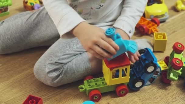 Cute little girl sitson floor and playing with colorful building blocks. - Footage, Video