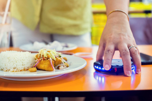Ασύρματο μηχάνημα κλήσης ουρά στο χέρι του πελάτη με το φαγητό. Σύστημα ασύρματης κλήσης με συναγερμό κόκκινου φωτός για εστιατόριο, καφετέρια. - Φωτογραφία, εικόνα