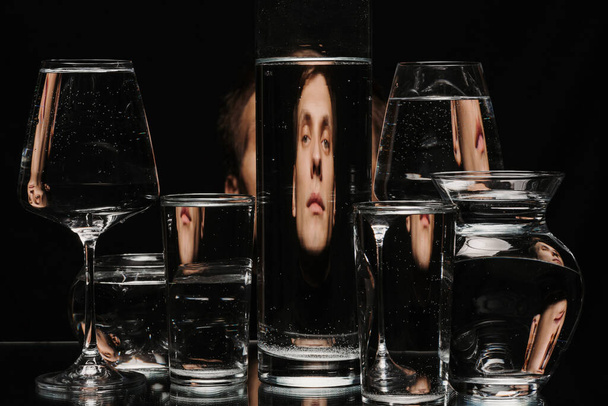 πορτρέτο ενός ανθρώπου μέσα από το γυαλί της δεξαμενής με νερό με τις αντανακλάσεις και τις παραμορφώσεις - Φωτογραφία, εικόνα