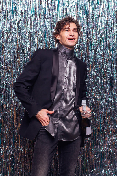 Holidays concept - happy tipsy man with bottle of champagne and wine glass at christmas or new year party on a sparkle background. - Valokuva, kuva