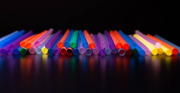 Close-up weergave van kleurrijke plastic rietjes op een zwarte achtergrond. Begrip verbod in de EU. - Foto, afbeelding