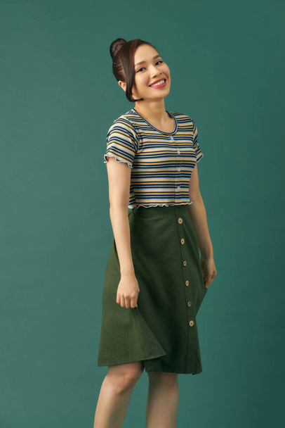 Retrato de una joven hermosa mujer asiática en ropa casual posando sobre un fondo verde - Foto, Imagen