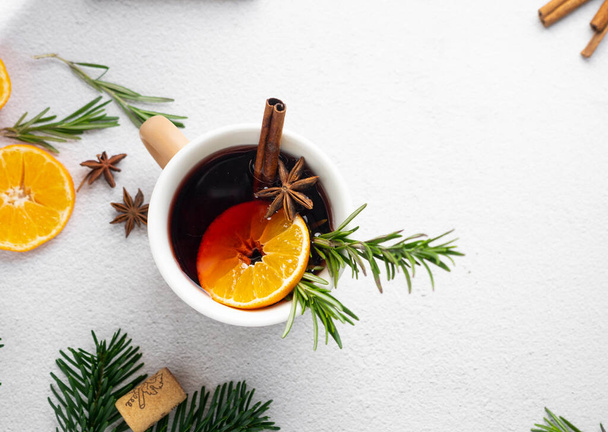 mulled red wine with spices. in a brown mug. on a light background with fir branches and tangerines - Fotoğraf, Görsel