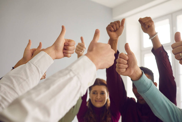 Group of people raising hands and showing thumbs-up, celebrating a job well done - 写真・画像