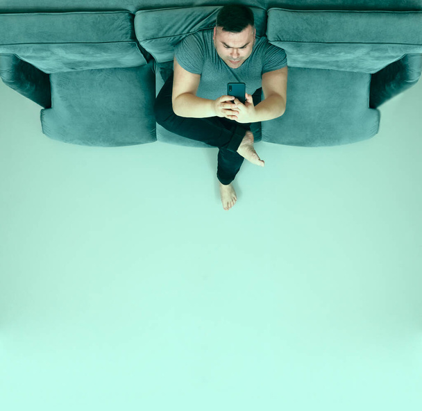 middle aged man looking at screen of mobile phone, smartphone and relax on sofa.  - 写真・画像