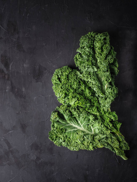 Fresh green kale leaf on dark table. Overhead shot with copy space. - Foto, afbeelding