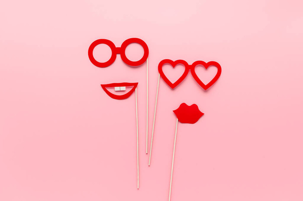 Czerwony papier strona akcesoria okulary i usta na pastelowym różowym tle. Pojęcie Homoseksualizm, lesbijska miłość. Widok z góry, kreatywne płaskie łóżko. Kartka okolicznościowa - Zdjęcie, obraz
