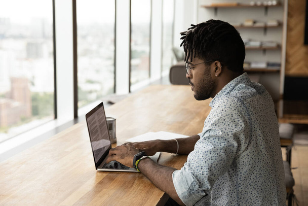 Millennial biracial man work online on computer at home - Фото, изображение