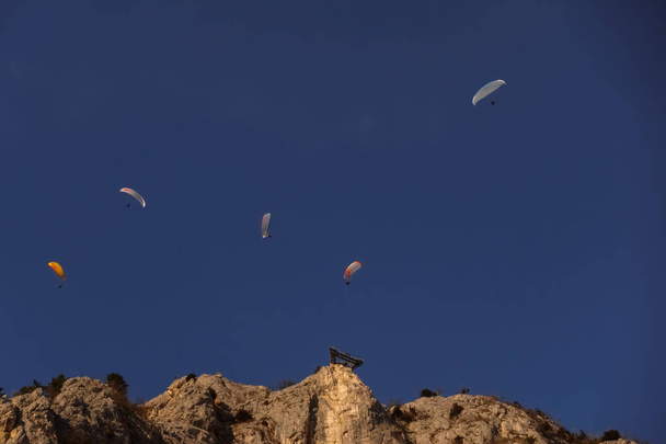 深い青空の5つのパラグライダーと空中散歩の岩壁 - 写真・画像