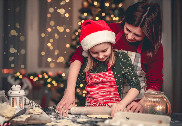Little girl in santa hat cutting cookies - Foto, Bild