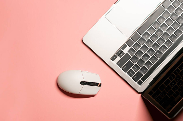 Horizontal plano poner foto minimalista con un ordenador portátil gris plateado, y un ratón inalámbrico de color blanco sobre un fondo rosa. - Foto, imagen