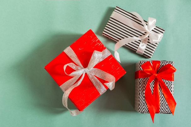 Christmas gifts on a green background. Different packed boxes with tied bows top view. happy new year and christmas. the concept of shopping, gifts for the holidays. Flat lay. - Foto, imagen
