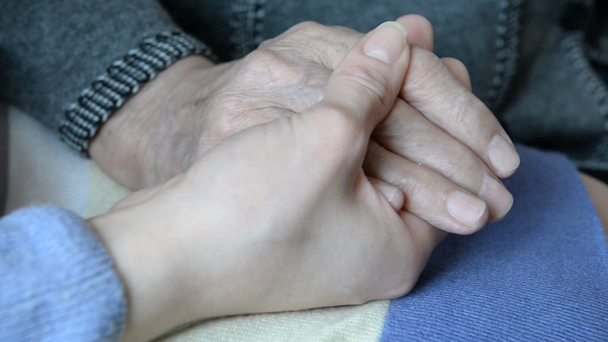 kéz a kézben. egy idős asszony a kezét, egy fiatal lány kezét - Felvétel, videó
