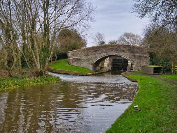 Bridge 108 ja alaportit Wharton 's Lock Shropshire Union Canal lähellä Beeston Cheshire, Englanti, Iso-Britannia. Vesi valuu lukon alapuolelta ohitustien Weir on näkyvissä vasemmalla. - Valokuva, kuva