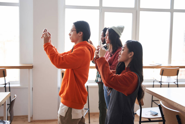Group of students standing in front of the whiteboard and shooting their home tasks - Fotografie, Obrázek
